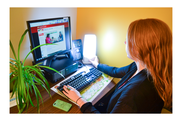 Woman using therapy light while on the computer in her office